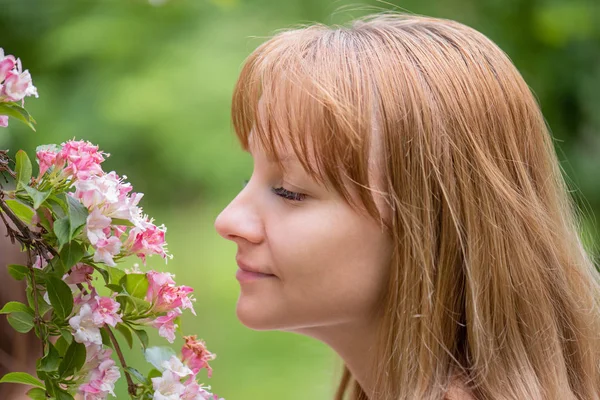 Mulher cheirando flores no parque — Fotografia de Stock