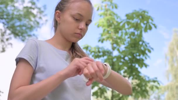 Adolescente Con Auriculares Enciende Música Reloj Inteligente Ejecuta Parque Verde — Vídeos de Stock