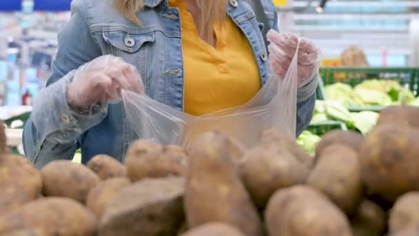 ジャガイモを選ぶ保護手袋の女性の手 Covid 19コロナウイルス流行中にスーパーマーケットで食品を購入する 大人の女の子は隔離と自己分離中に食べ物に蓄積します — ストック動画