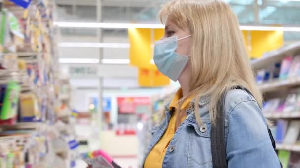 Junge Frau Mit Medizinischer Gesichtsmaske Kauft Schreibwaren Für Die Schule — Stockvideo