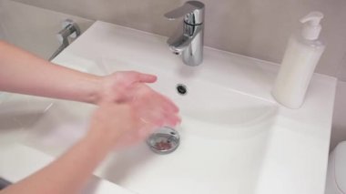 Kadın eli su musluğunu çeviriyor. Coronavirüs enfeksiyonunu önlemek için ellerini banyoda sabunla yıkayan kız. Covid-19. Yetişkin kadın musluğu kapatıyor.