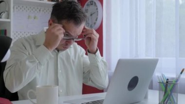 Ev ofisinde bilgisayarla çalışan gözlüklü yakışıklı bir iş adamı. Masada oturan, bilgisayarda yazan serbest çalışan bir erkek. İnternette evden çalışmak, uzak bir iş.. 