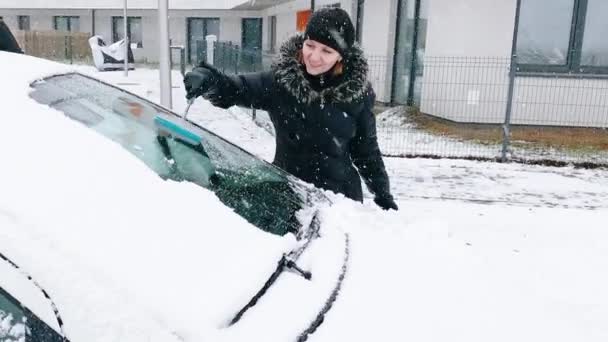 Kvinna rengöring bil från snö — Stockvideo