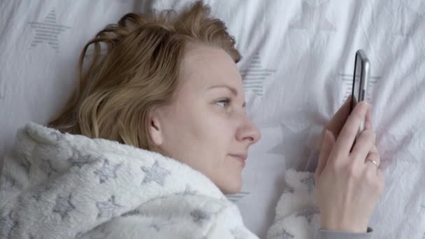 Жінка використовує мобільний телефон на ліжку — стокове відео