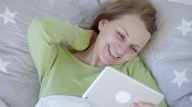 Yatakta tablet kullanan kadın