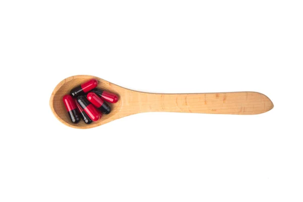 Pilules dans une cuillère en bois — Photo