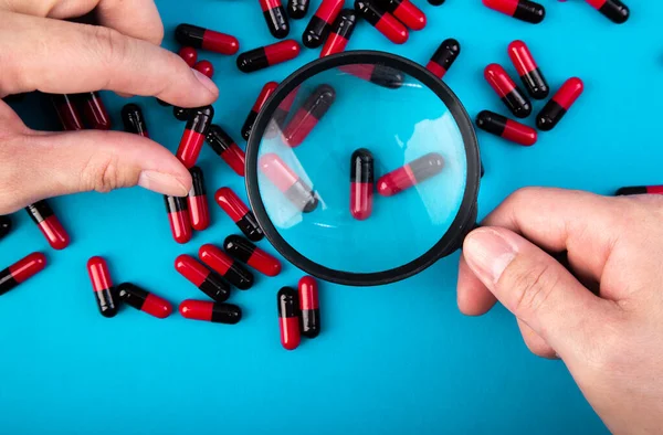 薬を見る虫眼鏡を手に 医学実験の概念 — ストック写真