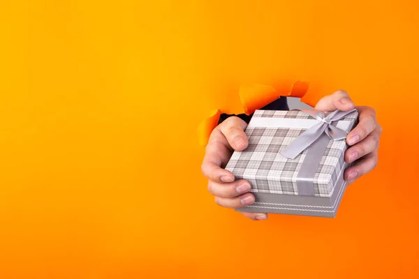 Mano Sosteniendo Regalo Través Papel Desgarrado Naranja —  Fotos de Stock