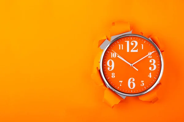 引き裂かれたオレンジの紙から出てくる時計 スペースのコピー — ストック写真