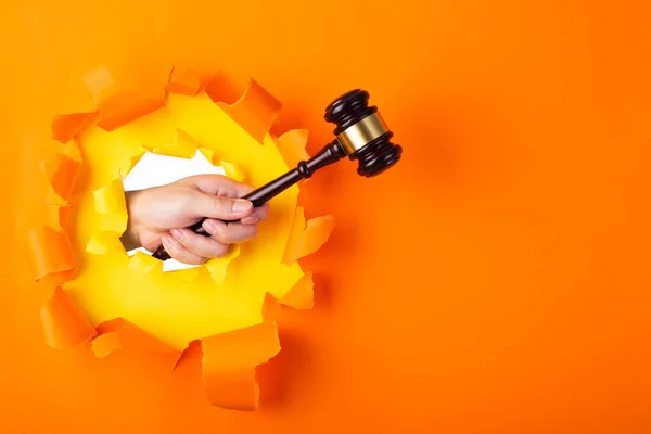 Hand Met Hamer Van Een Rechter Door Gescheurde Oranje Papieren — Stockfoto