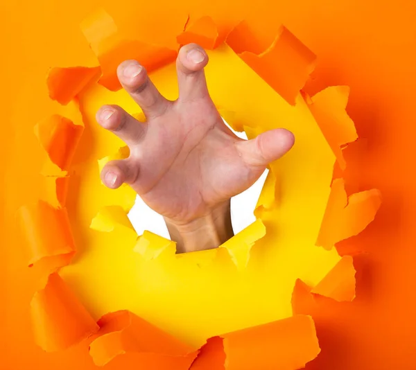 Man Hand Med Ilska Känsla Genom Ett Hål Orange Papper — Stockfoto