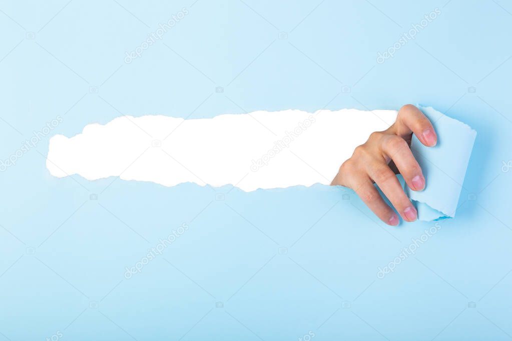 Hand tearing color paper background revealing copy space