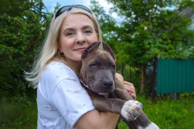 The blonde holds in her arms a puppy of the American Staffordshire Terrier