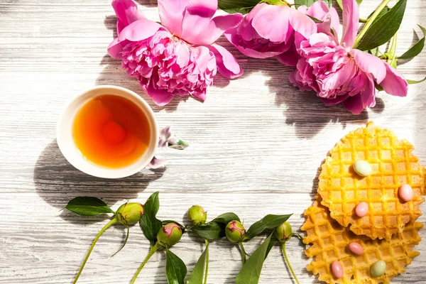 一杯绿茶和春天的牡丹花在古老的木制背景上 有华夫饼和奶糖 — 图库照片
