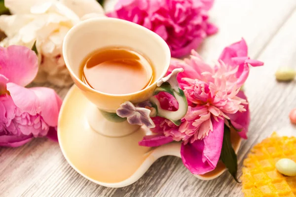 一杯绿茶和春天的牡丹花在古老的木制背景上 有华夫饼和奶糖 — 图库照片