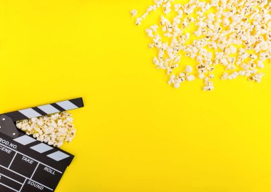 Sinema arka plan. Filmi izlerken. Patlamış mısır ve Klaket üzerinde sarı arka plan üstten görünüm alanı Kopyala