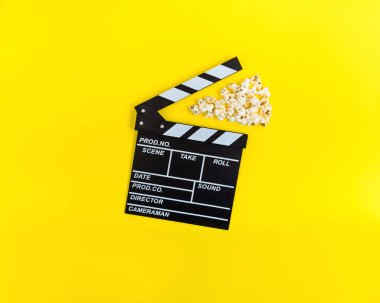Sinema arka plan. Filmi izlerken. Patlamış mısır ve Klaket üzerinde sarı arka plan üstten görünüm alanı Kopyala