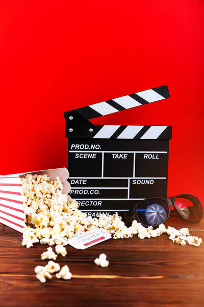 Cinema clapperboard, popcorn, tickets and 3d glasses on wooden planks with copy space