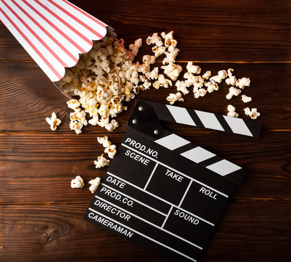 Cinema background. Film watching. Popcorn and clapperboard on wooden planks with copy space