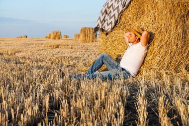 saman haystacks içinde hasat sonrası dinlenme bir hasır şapka giyen adam