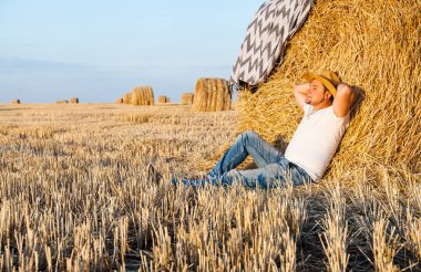 saman haystacks içinde hasat sonrası dinlenme bir hasır şapka giyen adam