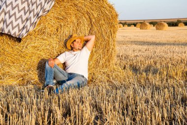saman haystacks içinde hasat sonrası dinlenme bir hasır şapka giyen adam
