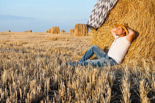 saman haystacks içinde hasat sonrası dinlenme bir hasır şapka giyen adam