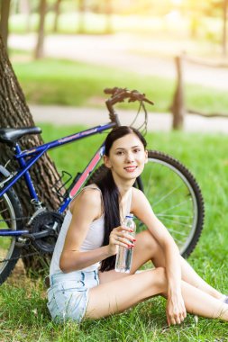 Şehir Parkı içme suyu çimenlerin üzerinde rahatlatıcı Bisiklet ile güzel bir kız. Aktif insanlar. Açık havada