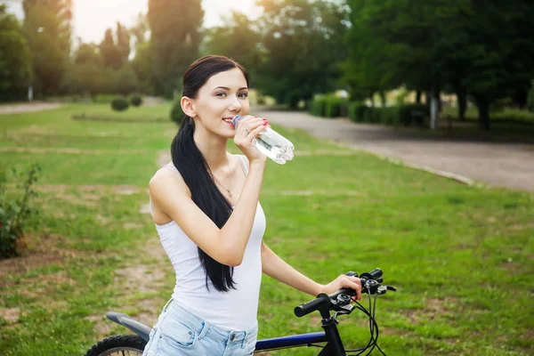 Bisiklet Şehir Parkı içme suyunda rahatlatıcı güzel kızla. Aktif insanlar. Açık havada
