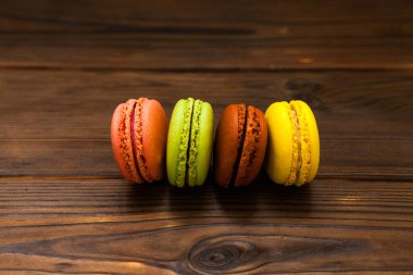 Macaroons arka plan, kahverengi ahşap masa üzerinde renkli kurabiye