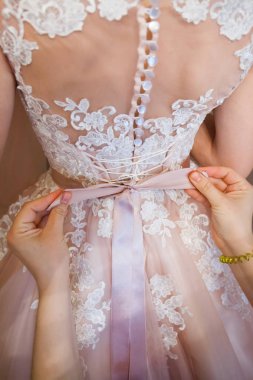 Düğün kavramı. Bir close-up gelinin geri bir ihale dantel gelinlik. Elbise sabitleme işlemi.