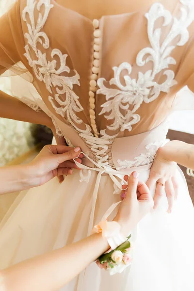 Wedding concept. A close-up of the bride\'s back in a tender wedding lace dress. The process of fastening the dress.