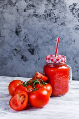 Domates suyu Mason kavanoza ve taze üzüm domates bütün ve yarısı rustik masa