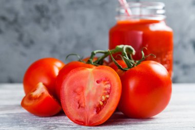 Domates suyu Mason kavanoza ve taze üzüm domates bütün ve yarısı rustik masa