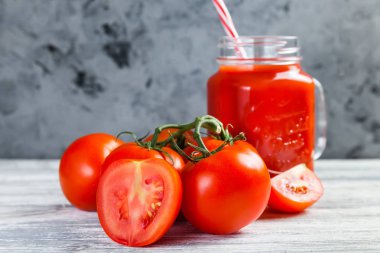 Domates suyu Mason kavanoza ve taze üzüm domates bütün ve yarısı rustik masa