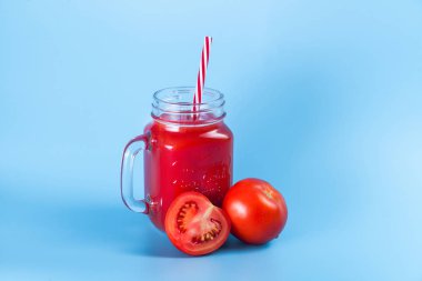 Mason kavanoza ve taze üzüm domates ve bütün mavi ıslak zemin üzerine yarım domates domates suyu