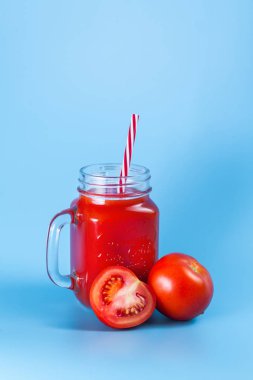 Mason kavanoza ve taze üzüm domates ve bütün mavi ıslak zemin üzerine yarım domates domates suyu