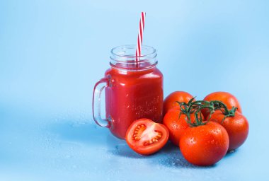 Mason kavanoza ve taze üzüm domates ve bütün mavi ıslak zemin üzerine yarım domates domates suyu