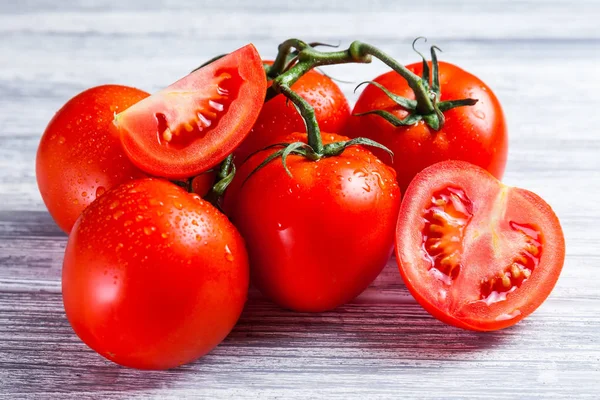 Fresh grape tomatoes with for use as cooking ingredients with a halved tomato in the foreground on rustic table