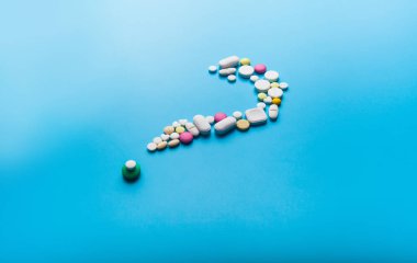 Beyaz arka plan üzerinde bir soru işareti şeklinde hapları