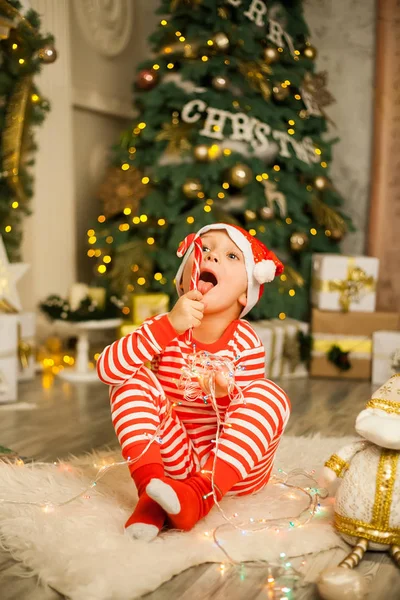 Cute Little Boy Striped Red Pajamas Hat Lies Christmas Tree — Stock Photo, Image