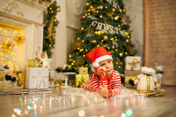 Cute Little Boy Striped Red Pajamas Hat Lies Christmas Tree — Stock Photo, Image