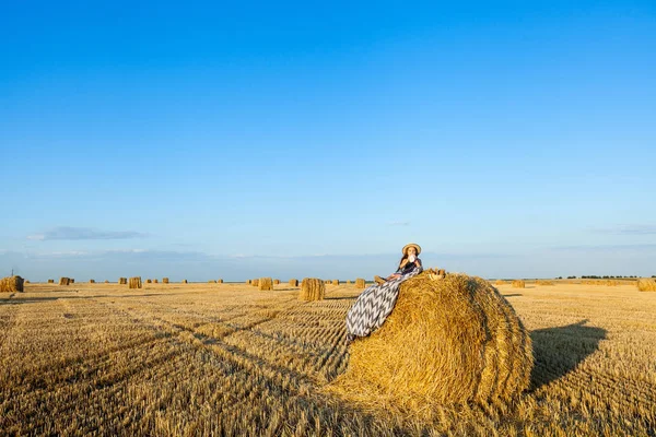 Criança pequena bonito no campo de centeio com pilhas de feno no pôr do sol . — Fotografia de Stock