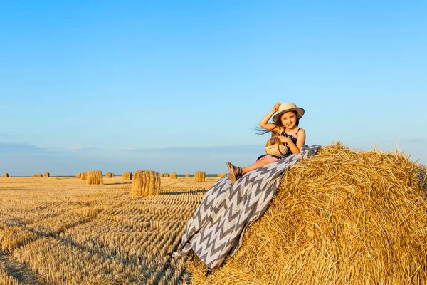 Mignon petit enfant dans le champ de seigle avec des piles de foin au coucher du soleil . — Photo