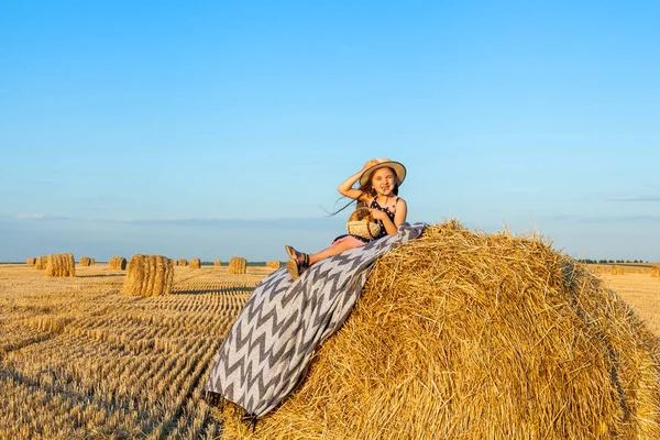 Mignon petit enfant dans le champ de seigle avec des piles de foin au coucher du soleil . — Photo