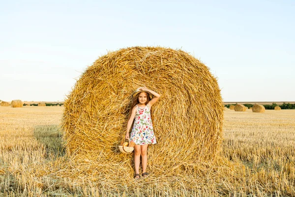 Bedårande flicka i råg fält på solnedgången med en korg med bröd. — Stockfoto