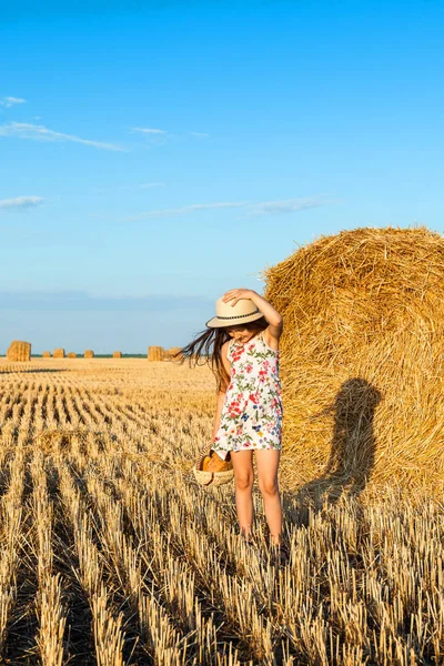 Adorabile ragazza nel campo di segale al tramonto con un cesto di pane . — Foto Stock