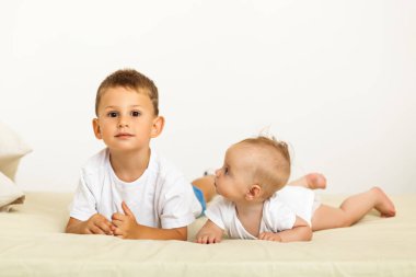 Erkek ve kız kardeşin portresi. İki sevimli çocuk yatakta yatıyor