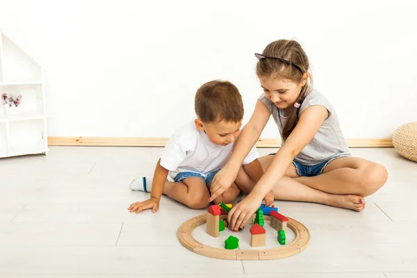 Schattig klein meisje en jongen spelen met speelgoed door het huis — Stockfoto