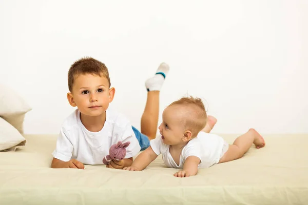 Portrait of brother and sister. Two cute children lying on bed — Stock Photo, Image